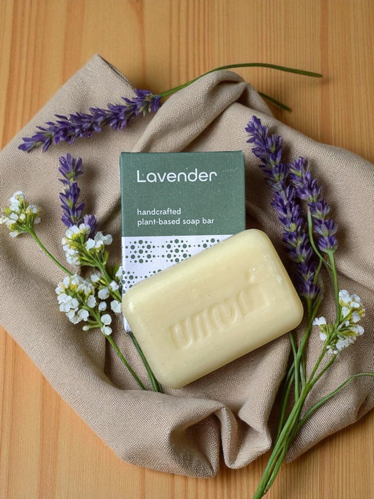 lavender soap on a light wood table with a linen cloth and purple and white flowers