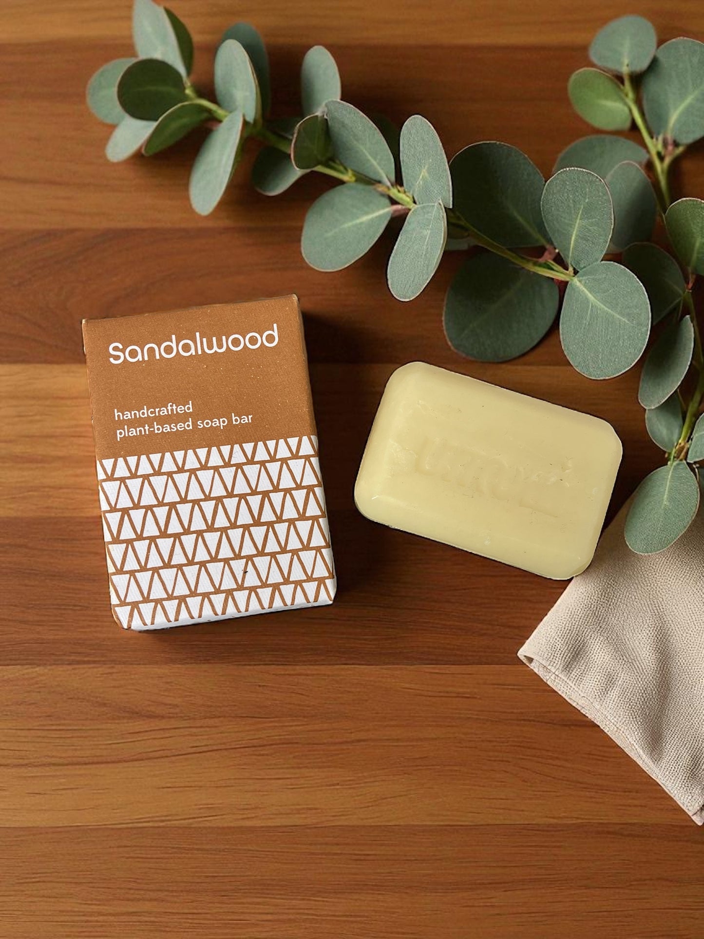 Sandalwood soap on a wooden table with a linen cloth and eucalyptus