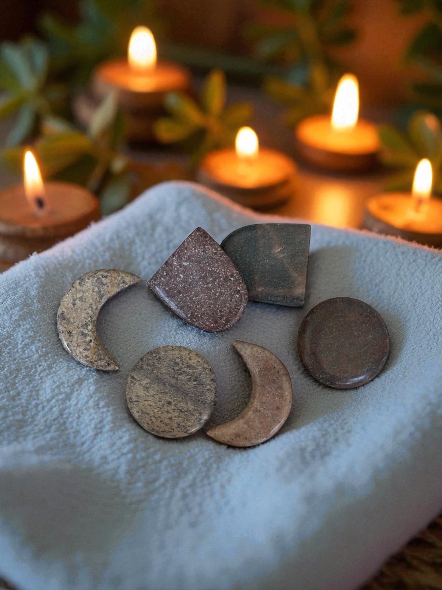Decorative stones on a white cloth with lit candles in the background