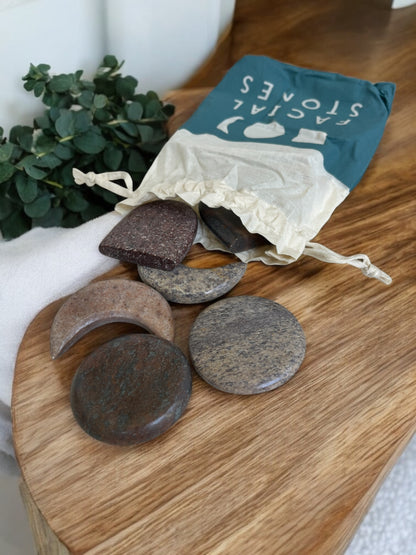 Set of stones on a wooden board with a drawstring bag labeled 'Facial Stones' in the background.