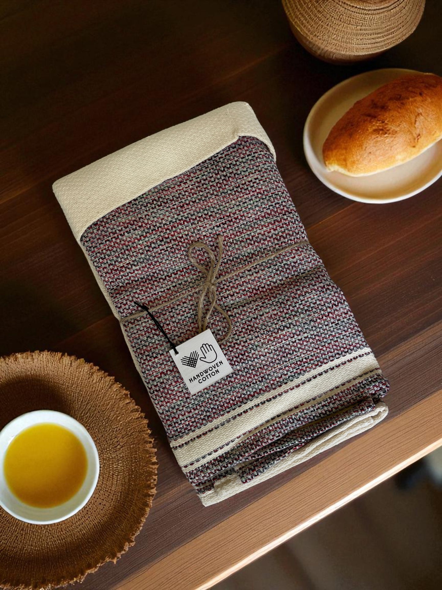folded Egyptian hand towel on a wooden table with bread and a dish of butter