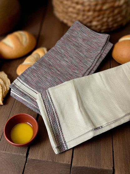 folded Egyptian hand towels on a wooden table with bread and a dish of butter