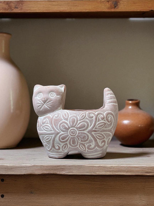 Ceramic cat-shaped vase with floral patterns on a wooden shelf with other decorative items.