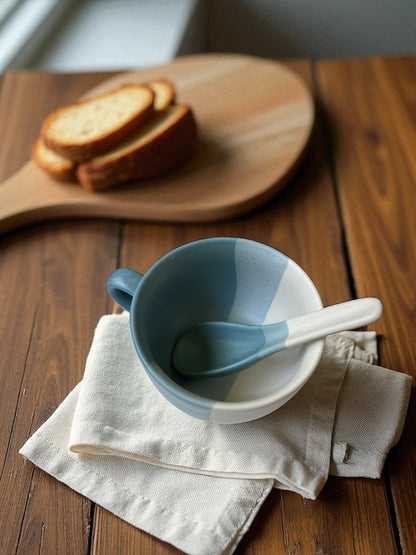 blue striped jumbo mug with matching spoon on a linen cloth with bread in the background