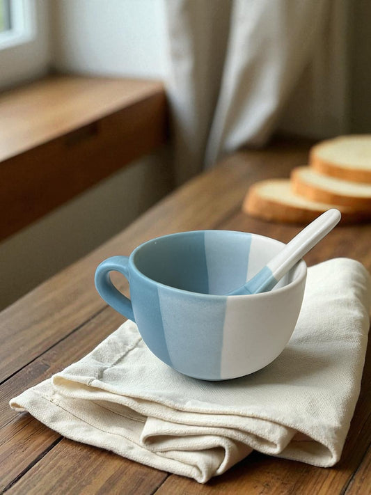 blue striped jumbo mug with matching spoon on a linen cloth with bread in the background