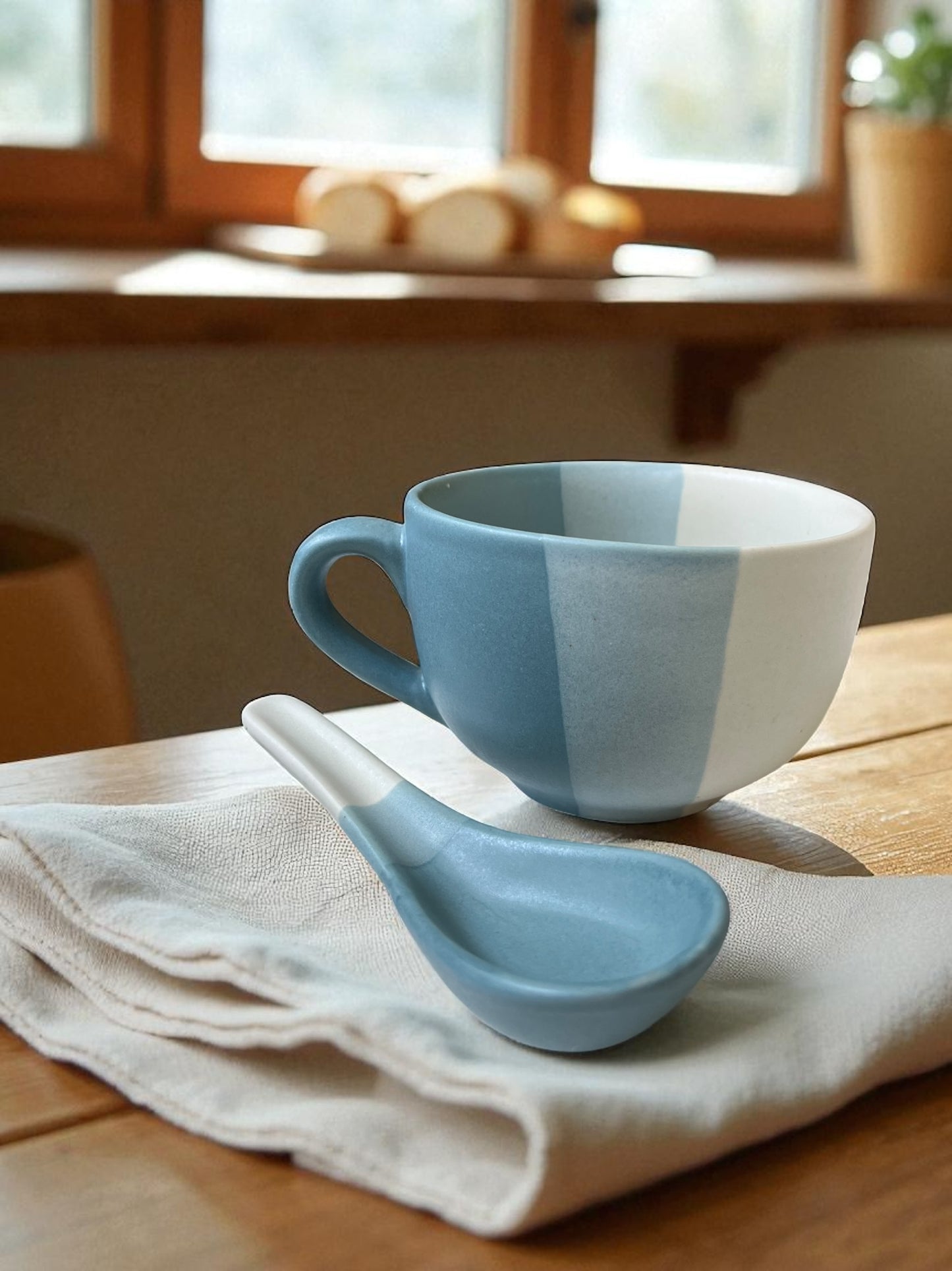 blue striped jumbo mug with matching spoon on a linen cloth with bread in the background