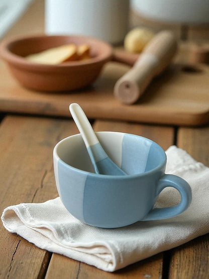 blue striped jumbo mug with matching spoon on a linen cloth with bread in the background