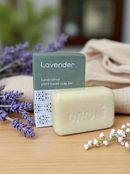 lavender soap on a light wood table with a linen cloth and purple and white flowers